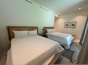 Une chambre d’hôtel avec deux lits, une table de chevet, une lampe et deux tableaux encadrés au mur.