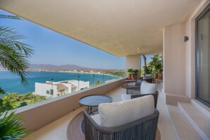 A balcony with wicker furniture, a small round table, and potted plants. - 4 bd Beach Chic Villa Ocean View - Iyari B4 (Punta de Mita)