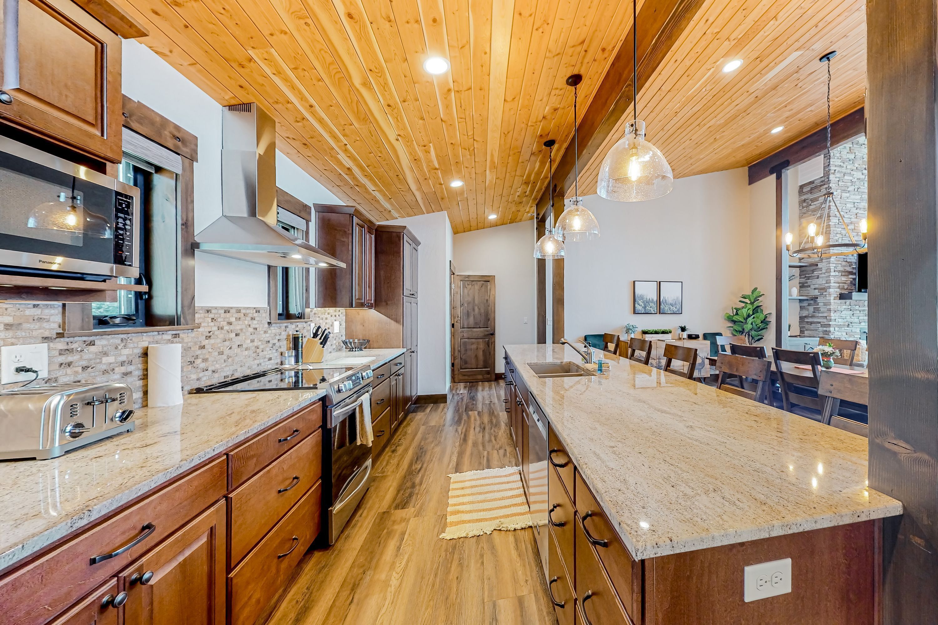 A kitchen with wooden cabinets, a granite countertop, a built-in microwave, and a central island with seating.