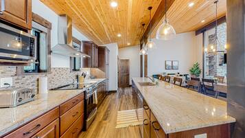 A kitchen with wooden cabinets, a granite countertop, a built-in microwave, and a central island with seating.