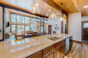 A spacious kitchen with a large island, wooden cabinets, and pendant lighting. - Leaning Pine Point in Harrison (Harrison)