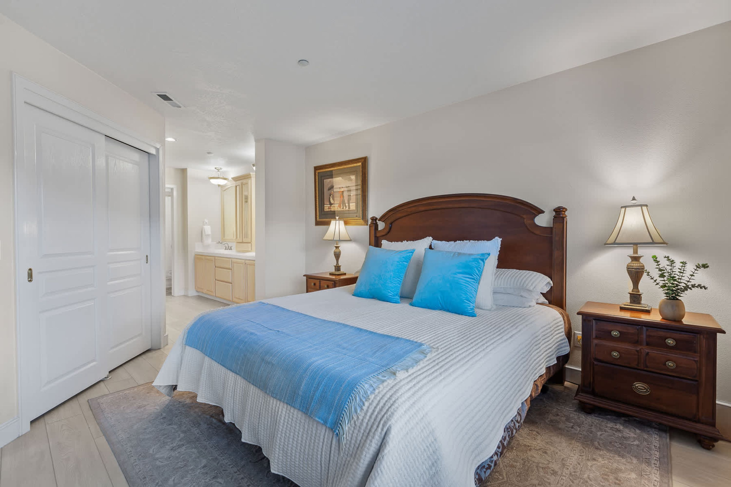 A bedroom with a bed, nightstands, a dresser, a mirror, and a door.