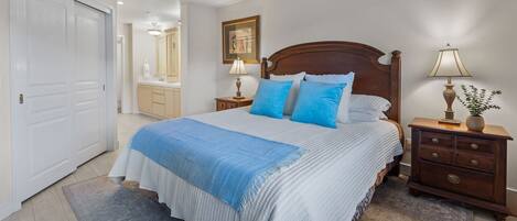 A bedroom with a bed, nightstands, a dresser, a mirror, and a door.