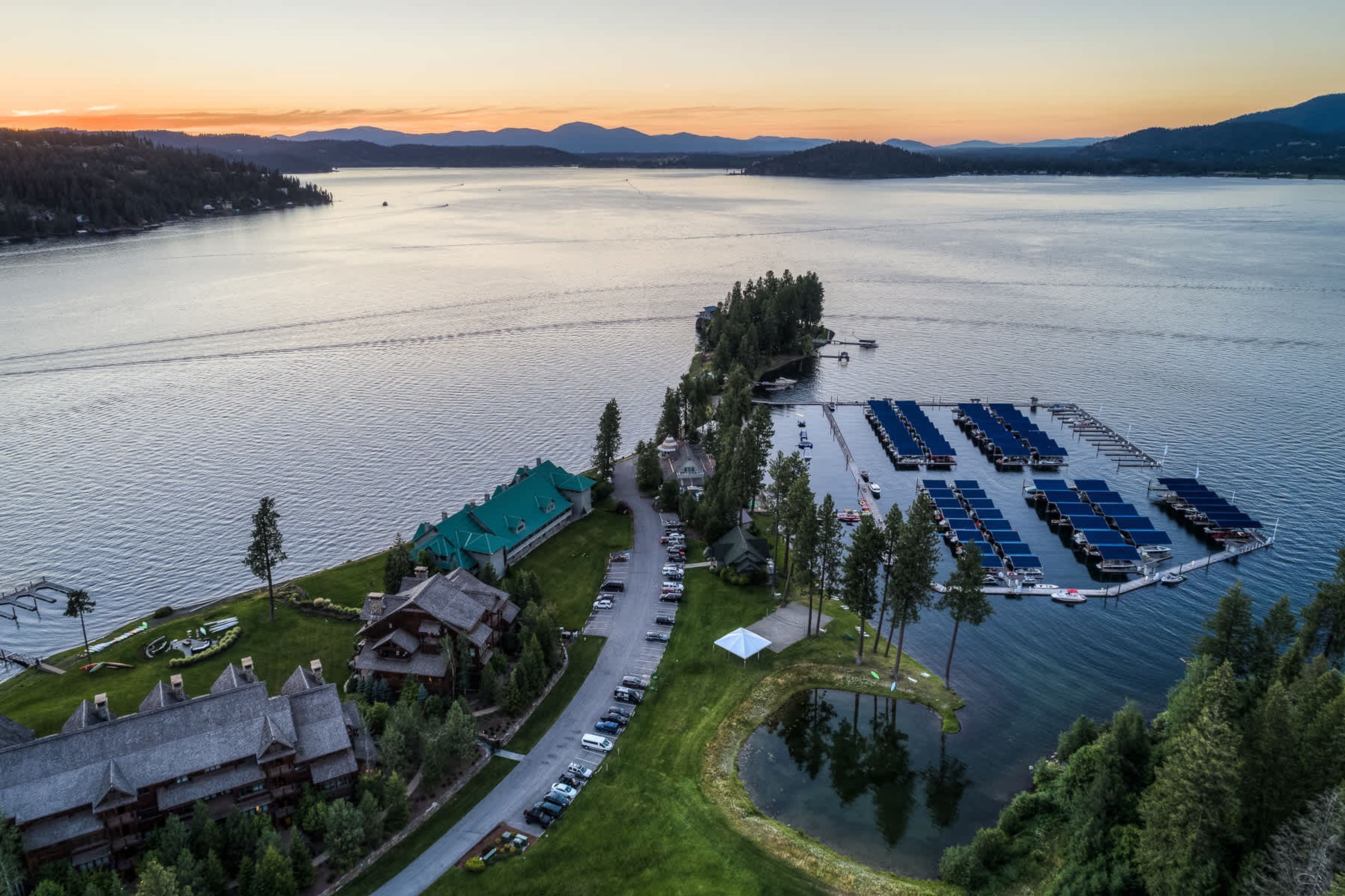 A lakeside hotel with a parking lot, solar panels, and a boat dock.