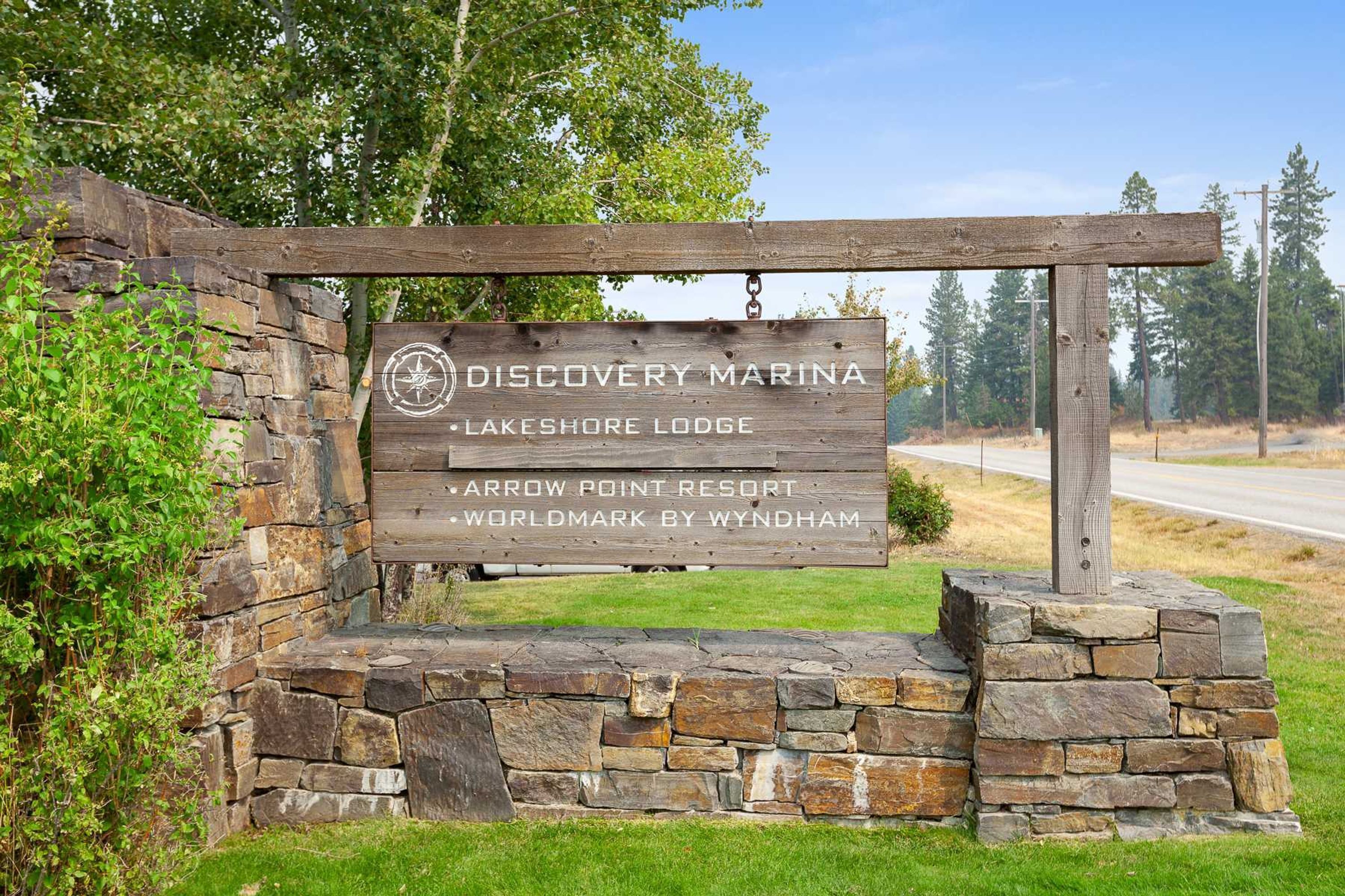 Un panneau en bois portant les noms suivants : Discovery Marina, Lakeshore Lodge, Arrow Point Resort et Worldmark by Wyndham.