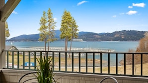 A balcony with a view of a lake, trees, and a distant shoreline. - Mountain Lake Getaway (Harrison)