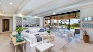 Ein geräumiger Wohnbereich mit einem weißen Sofa, einem Couchtisch und Blick auf eine Pool-Terrasse.