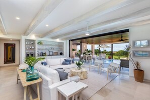 Ein geräumiger Wohnbereich mit einem weißen Sofa, einem Couchtisch und Blick auf eine Pool-Terrasse.
