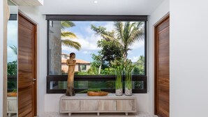 Ein modernes Interieur mit einem großen Fenster, einer Holzstatue und einer Holzbank mit Dekorationselementen.