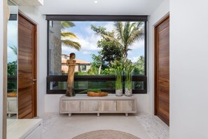 Ein modernes Interieur mit einem großen Fenster, einer Holzstatue und einer Holzbank mit Dekorationselementen.