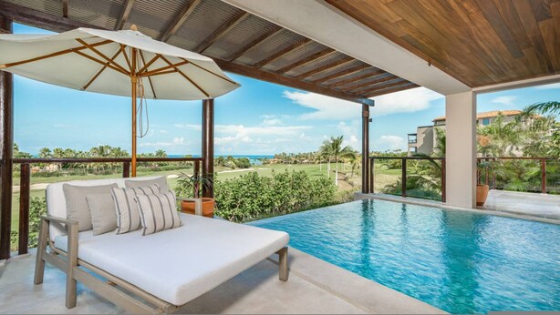 Eine Liegewiese am Pool mit Blick auf einen Golfplatz und das Meer.