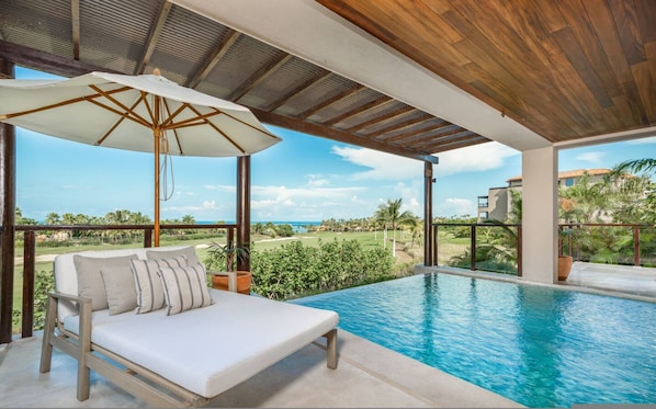 Eine Liegewiese am Pool mit Blick auf einen Golfplatz und das Meer.