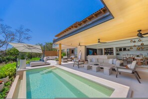 Ein moderner Poolbereich im Freien mit Liegemöglichkeiten und einer überdachten Terrasse.