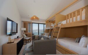 Ein kleines Hotelzimmer mit einem Etagenbett, einem Schreibtisch mit Lampe, einem Stuhl und einem Fernseher.