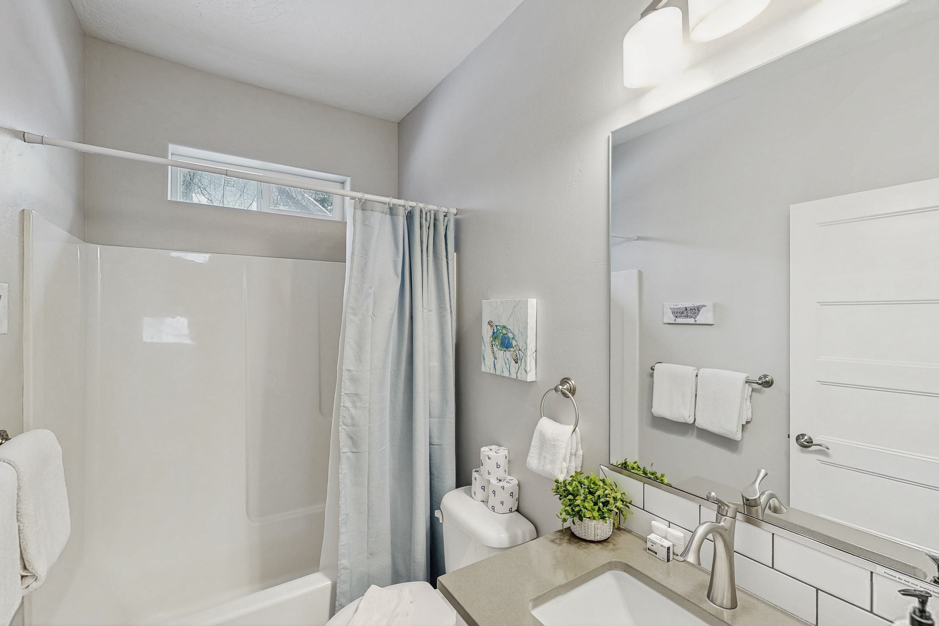 A modern bathroom with a shower, toilet, sink, and a large mirror.
