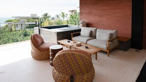 A modern living room with a sofa, two pouf chairs, a coffee table, and a view of the ocean. - Naya 6301 Tower VI in Punta De Mita (Punta de Mita)