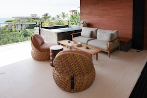 A modern living room with a sofa, two pouf chairs, a coffee table, and a view of the ocean. - Naya 6301 Tower VI in Punta De Mita (Punta de Mita)
