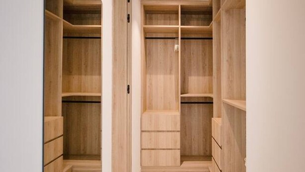 A walk-in closet with wooden shelving and drawers, a mirror, and a light fixture. - Naya 6301 Tower VI in Punta De Mita (Punta de Mita)