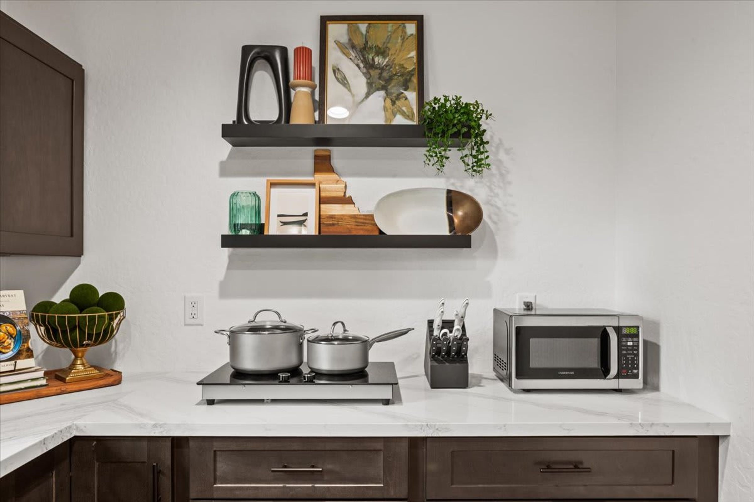 Una cucina con forno a microonde, fornelli e scaffali con utensili da cucina.