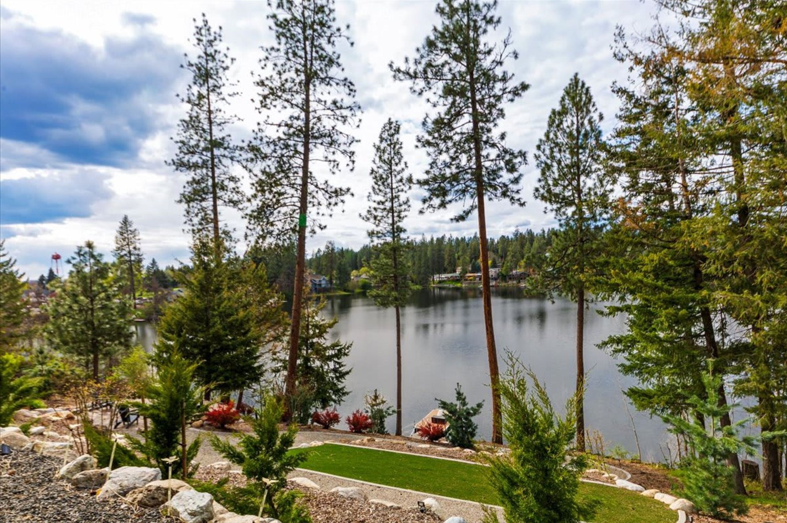 Un lac entouré de grands pins et bordé d’une pelouse bien entretenue.