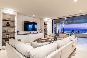 A modern living room with a flat-screen TV, a sofa, a coffee table, and a view of the ocean. - 3 bed 3 5 Bath Private Pool Wide Ocean Views Condo Cualli (Punta de Mita)