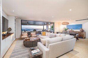 A modern living room with a large window, a sofa, a coffee table, and a dining area. - 3 bed 3 5 Bath Private Pool Wide Ocean Views Condo Cualli (Punta de Mita)