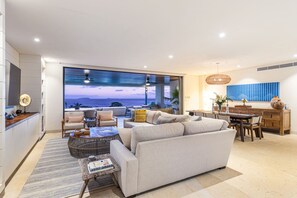 A modern living room with a large window, a sofa, a coffee table, and a dining area. - 3 bed 3 5 Bath Private Pool Wide Ocean Views Condo Cualli (Punta de Mita)