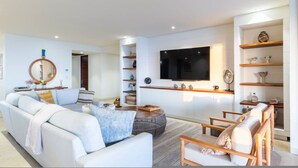 A modern living room with a sofa, armchairs, a coffee table, a TV, and built-in shelves. - 3 bed 3 5 Bath Private Pool Wide Ocean Views Condo Cualli (Punta de Mita)