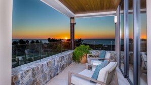 A balcony with a sunset view, stone wall, and outdoor furniture. - 3 bed 3 5 Bath Private Pool Wide Ocean Views Condo Cualli (Punta de Mita)