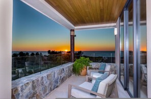 A balcony with a sunset view, stone wall, and outdoor furniture. - 3 bed 3 5 Bath Private Pool Wide Ocean Views Condo Cualli (Punta de Mita)