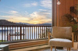 A balcony with a view of a lake, a chair, and a potted plant. - Cabin On The Lake in Harrison (Harrison)