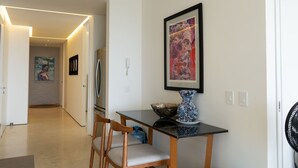 Ein Essbereich mit Tisch, Stühlen, einer Vase und einem gerahmten Bild an der Wand.