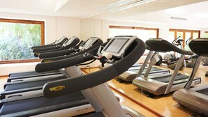 Une salle de sport équipée de plusieurs tapis de course, dotée d’un plancher en bois et de grandes fen êtres donnant sur un paysage verdoyant.