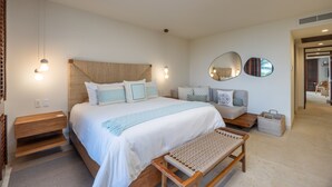 Une chambre à coucher avec un grand lit, des tables de chevet, un banc, un miroir et un luminaire fixé au mur.