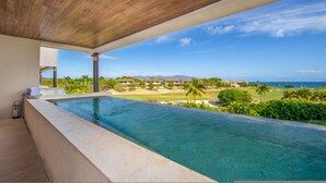 Une piscine avec vue sur un terrain de golf et l’océan.