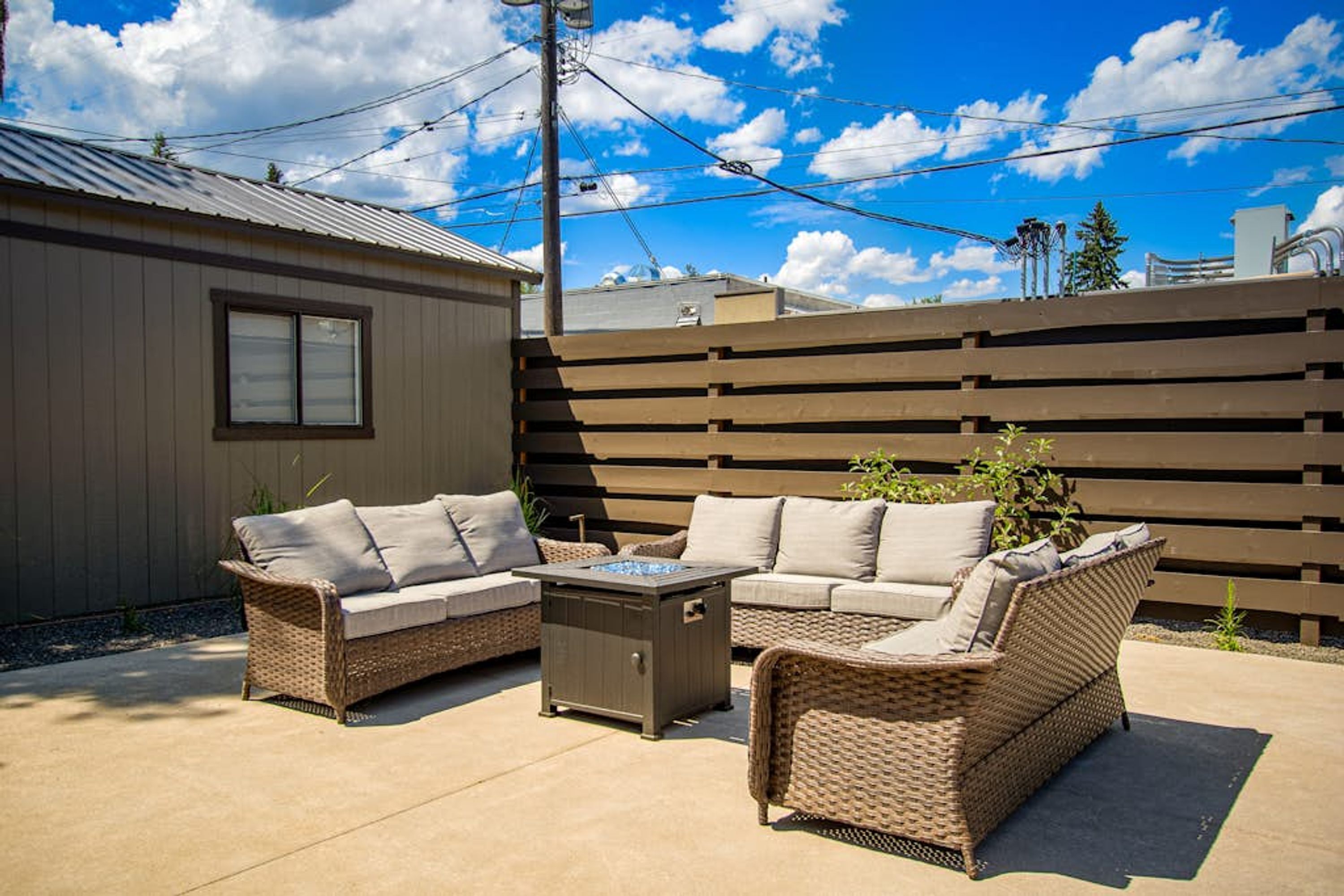 A patio with wicker furniture and a built-in fire feature.
