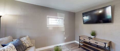 A living room with a sofa, coffee table, and a TV on the wall.