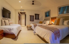 A hotel room with two beds, a TV, a ceiling fan, and artwork on the walls. - 3 Bed Condo Sleeps 12 With Pool Ocean View HK (Punta de Mita)