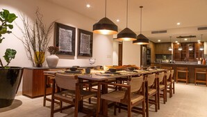A modern dining area with wooden furniture, pendant lighting, and a large vase with branches. - 3 Bed Condo Sleeps 12 With Pool Ocean View HK (Punta de Mita)