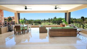 A spacious balcony with a dining area, two sofas, and a view of the ocean. - Gorgeous Remodeled Hacienda de Mita Condo - HDM 905 (Punta de Mita)