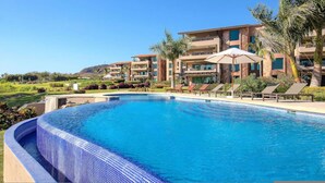 A hotel with a swimming pool, lounge chairs, and palm trees. - Gorgeous Remodeled Hacienda de Mita Condo - HDM 905 (Punta de Mita)
