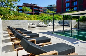 A poolside area with lounge chairs, a swimming pool, and a view of modern buildings. - Naya 5201 Tower V in Punta De Mita (Punta de Mita)