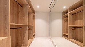 En moderne, tom walk-in garderobe med hylder i træ og et spejldør.