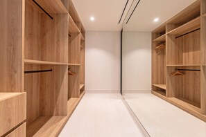 Ein moderner, leerer begehbarer Kleiderschrank mit Holzböden und einer Spiegel-Schranktür.