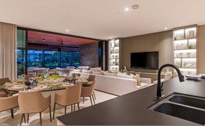Eine moderne Küche mit Essbereich, einem großen Fernseher und Blick ins Freie.