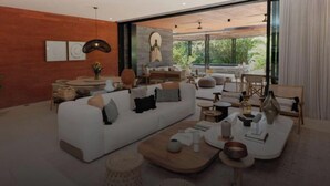 A modern living room with a white sofa, round coffee table, and a large window offering a view of greenery. - Naya 5102 Tower V in Punta de Mita (Punta de Mita)