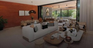 Ein modernes Wohnzimmer mit einem weißen Sofa, einem runden Couchtisch und einem großen Fenster mit Blick auf Grünflächen.