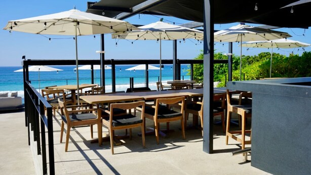 An outdoor seating area with tables and chairs, umbrellas, and a view of the ocean. - Naya 5102 Tower V in Punta de Mita (Punta de Mita)