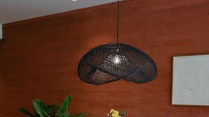 A round dining table with white wicker chairs, a vase with flowers, and a hanging light fixture. - Naya 5102 Tower V in Punta de Mita (Punta de Mita)