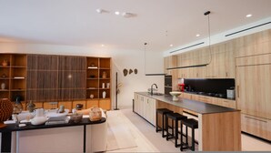 A modern kitchen with wooden cabinets, a central island with stools, and a built-in oven. - Naya 5102 Tower V in Punta de Mita (Punta de Mita)